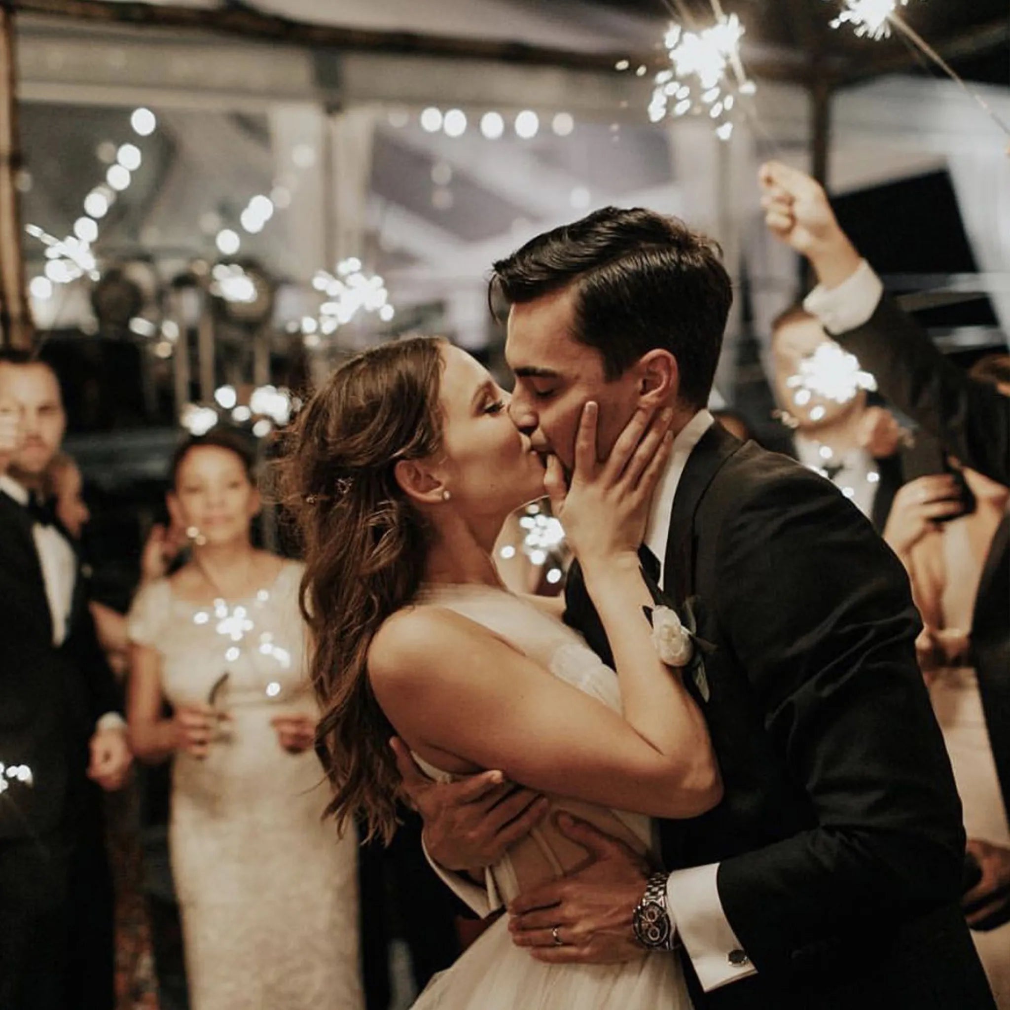 newlyweds kissing with wedding sparklers behind them